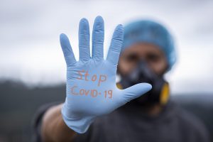 Healthcare worker with gloved hand up saying stop COVID-19