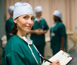 A woman in scrubs holding a clipboard.
